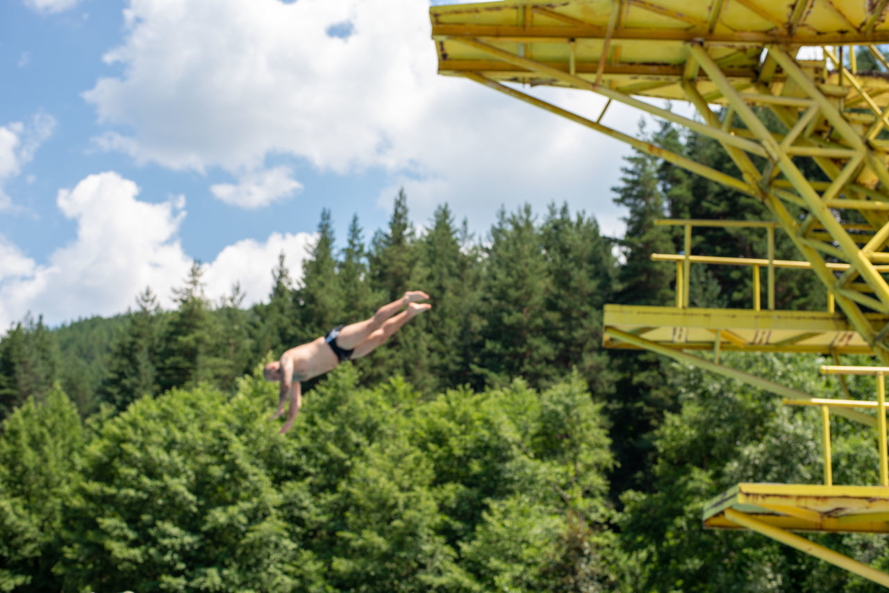 LOW ANGLE VIEW OF MAN JUMPING AGAINST SKY