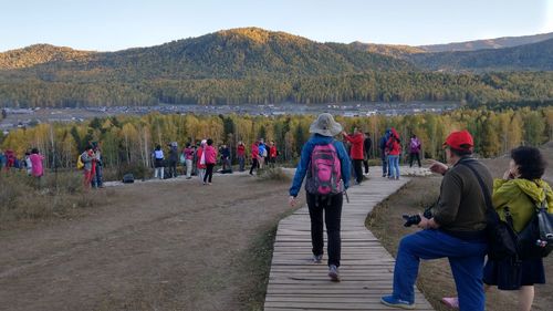 Rear view of people standing on mountain against sky