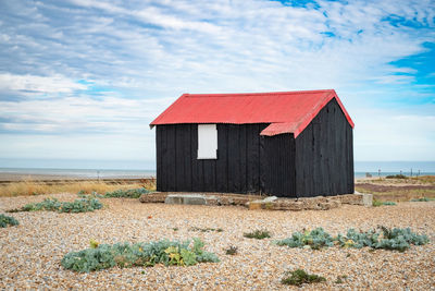 Wooden hut on beach against sky