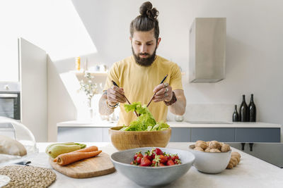 Young man preparing food on table at home