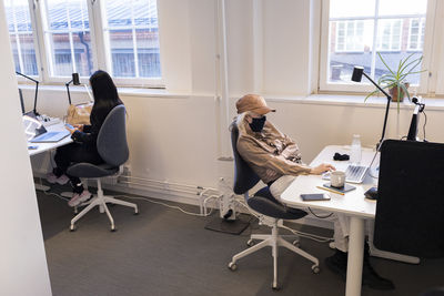 Women in face masks working on laptops in office