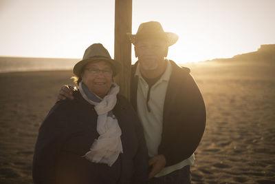 Portrait of couple standing at beach against sky