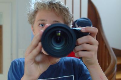 Portrait of boy photographing with camera at home