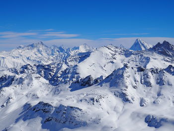 Scenic view of snow covered mountains against blue sky