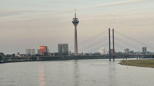 Bridge over river by buildings against sky in city