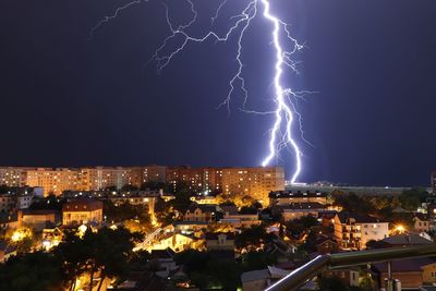 Lightning in city against sky at night