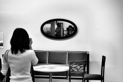 Rear view of woman standing on table at home