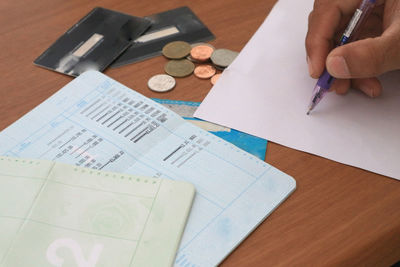 High angle view of hand holding paper on table