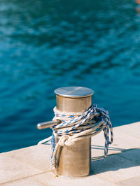 Close-up of rope tied to bollard against blue sky