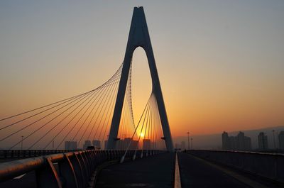 Low angle view of suspension bridge against sky during sunset