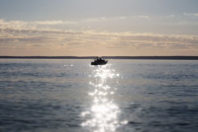 Boat sailing in sea against sky during sunset