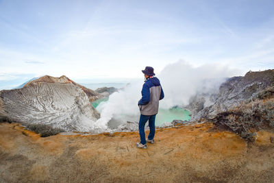 Side view of man standing on mountain against sky