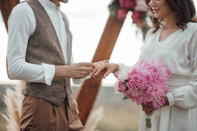 Midsection of couple holding flower bouquet