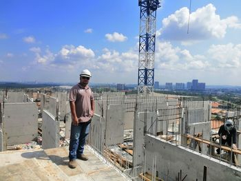 Portrait of construction worker on construction site against cloudy sky