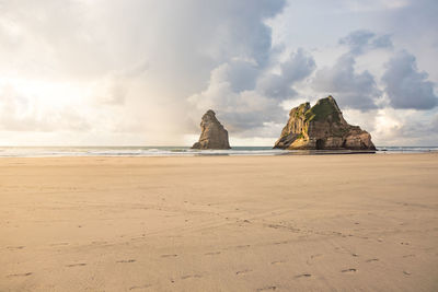 Rock formations on beach against sky