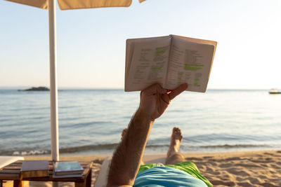 Mature man lying on a sunbed and reading a book at sunset. summer vacation concept.