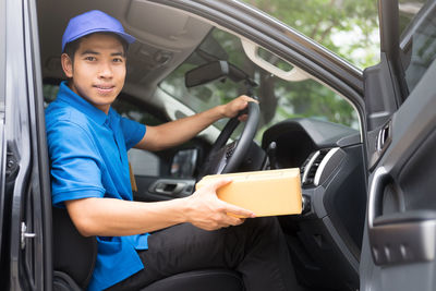 Portrait of male worker delivering package in delivery van