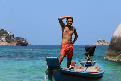 Young man standing on sea against clear sky