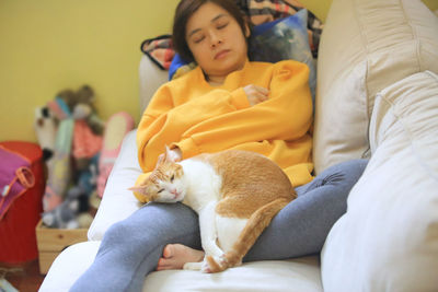 High angle view of woman with cat sleeping on sofa at home
