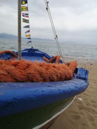 Close-up of fishing boat on sea shore against sky