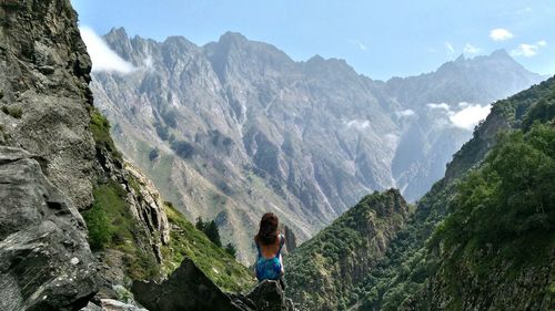 Rear view of woman standing on rocky mountains