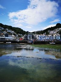 Buildings by river against sky in town
