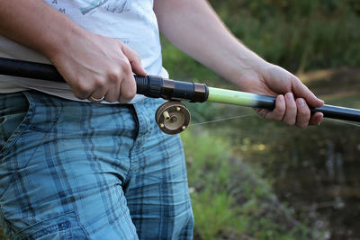 Midsection of man holding camera while standing on land