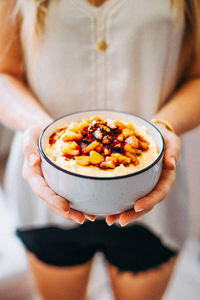 Midsection of woman holding breakfast in bowl at home