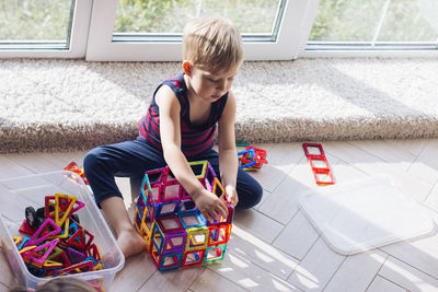The child is playing with a multi-colored magnetic constructor, building a tower. educational toys 