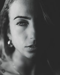 Close-up portrait of young woman against black background
