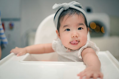 Portrait of cute baby girl on high chair