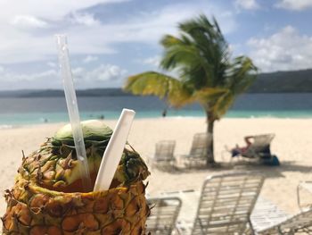 Close-up of drink at beach against sky