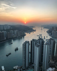 High angle view of buildings by sea against sky during sunset