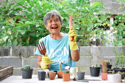 Happy senior woman planting plants at back yard