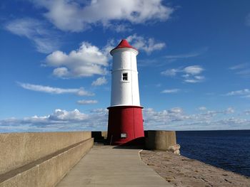 Lighthouse by sea against sky