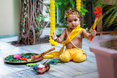 Adorable infant dressed as hindu god krishna cute facial expression with flute at janmashtami