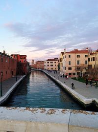 Canal amidst buildings in city against sky