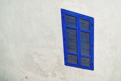 Low angle view of blue window on wall of building