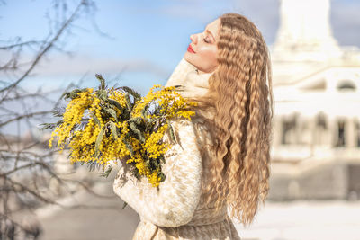 A woman with a bouquet of yellow acacia flowers. spring holiday - march 8, easter, women's day