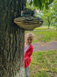 Boy standing by tree trunk