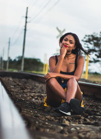Young woman looking away while sitting on railroad track