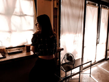 Side view of woman sitting at home