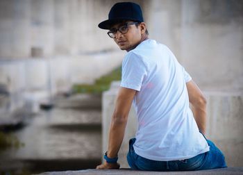 Portrait of young man sitting on retaining wall