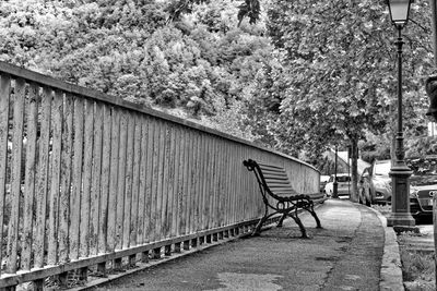 Empty bench on footpath in city