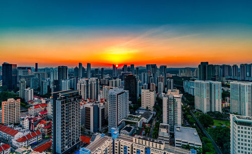 High angle view of modern buildings in city against sky during sunset