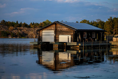 House by lake against sky
