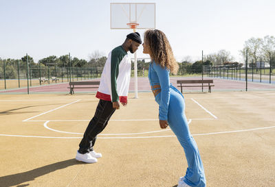 Male and female friends leaning over basketball court