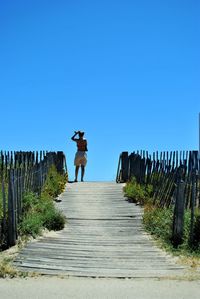 Rear view of woman walking against blue sky