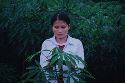 Young woman holding while standing by plants