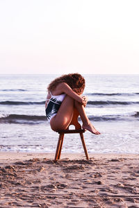 Woman on beach against clear sky